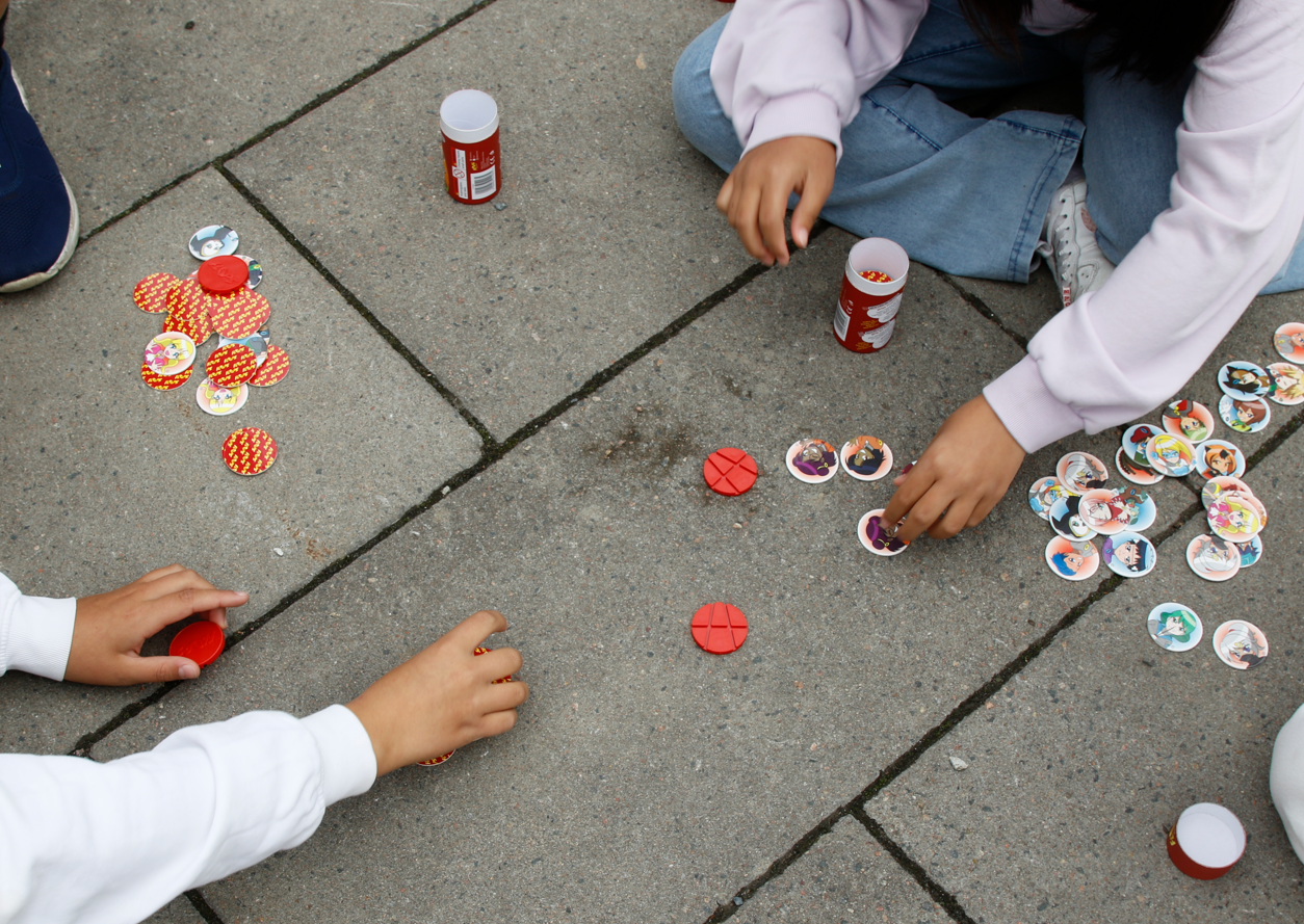 Friends playing FLOPS with colourful Magis discs and red Hitters on the playground